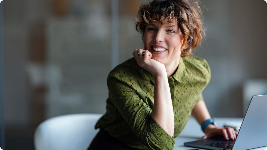 Smiling colleague seated beside a laptop